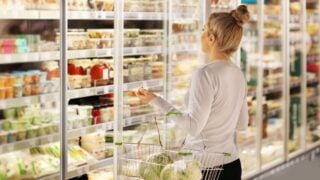 Woman choosing frozen food from a supermarket freezer