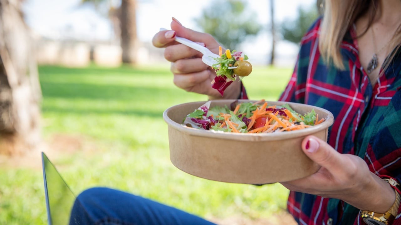 Close up of a salad being eaten by a girl sitting in a public park, vegan food, healthy lifestyle