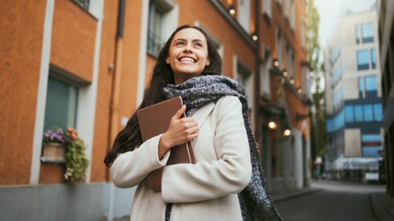 Travel, tourist and book with a sightseeing woman in the city traveling for tourism or vacation. Thinking, journal and traveling with a young female overseas or abroad for holiday in an urban town