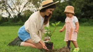 Mother and her baby daughter planting tree together in garden