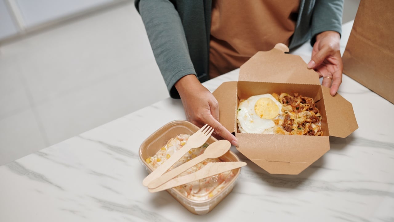 Hands of housewife opening box with delicious food delivered from local restaurant