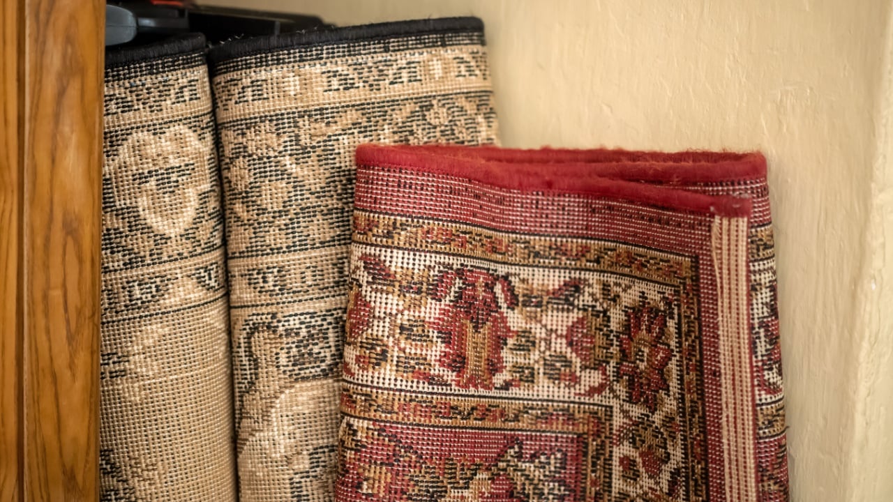 Old unused decorative carpets stored away, home carpet storage, garage sale items, used second hand household goods abstract concept, getting rid of, nobody, object closeup, no people. Two carpets