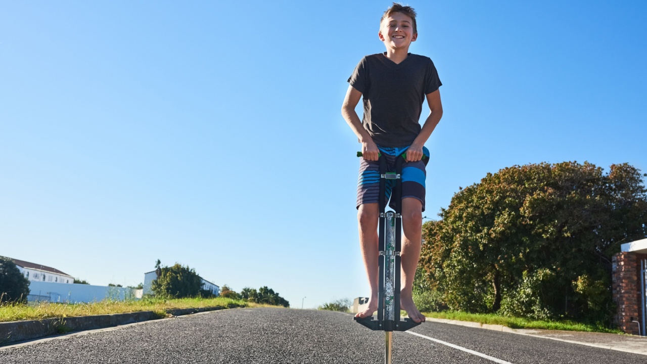 Lets bounce. Full length portrait of a young boy bouncing on a pogo stick outside.
