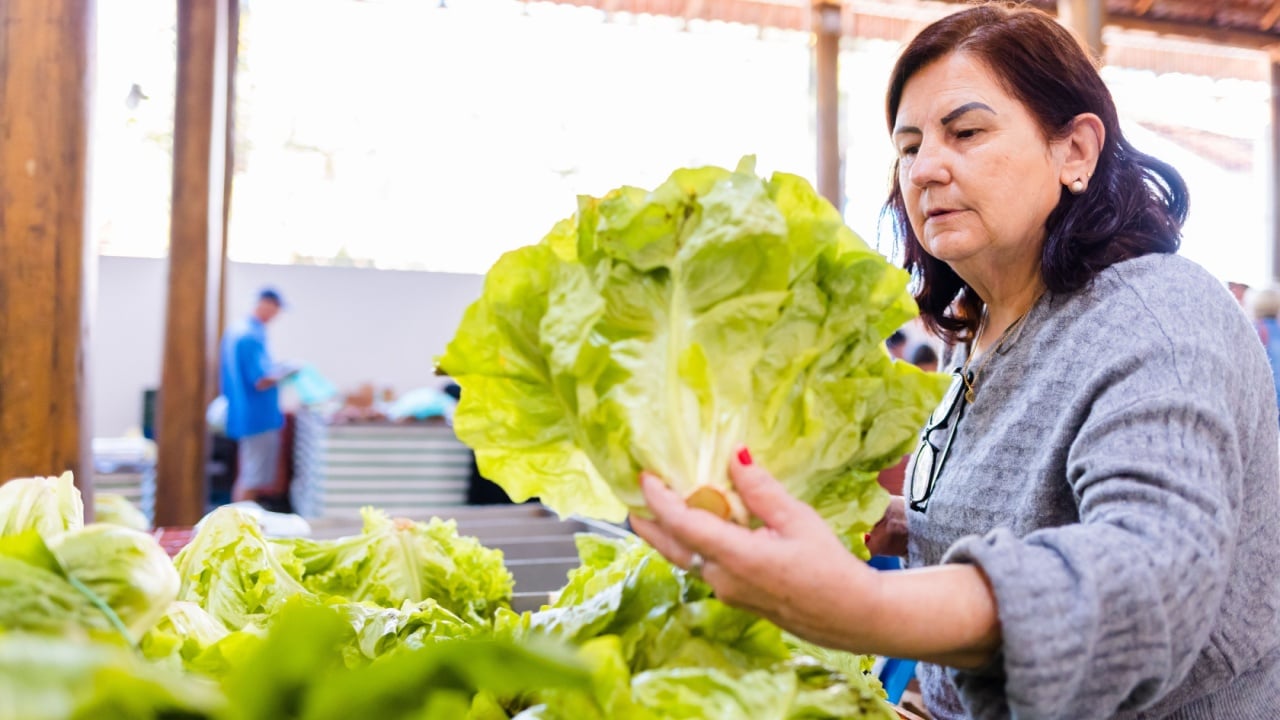 Mature woman choosing lettuces to buy at farmers market
