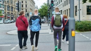 Group of people are crossing city road on green light of traffic light