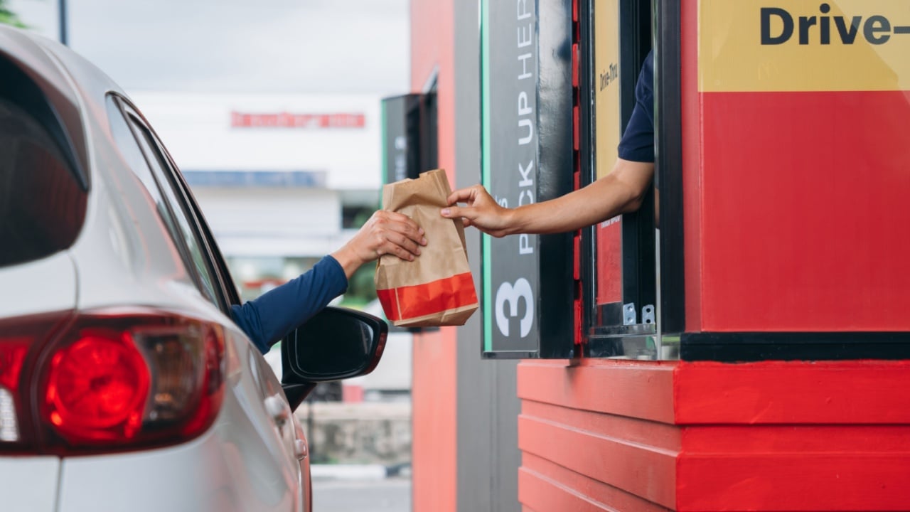 Young Man receiving coffee at drive thru counter.