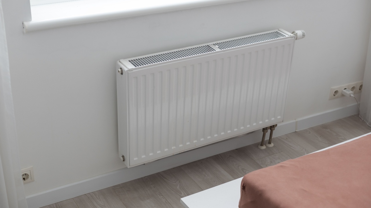 White heater with radiator and a modern thermostat on the wall in an apartment
