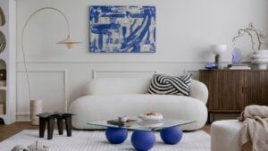 Cozy composition of living room interior with mock up poster frame, glass coffee table, stylish white sofa, pillow, wooden sideboard, lamp and personal accessories. Home decor.