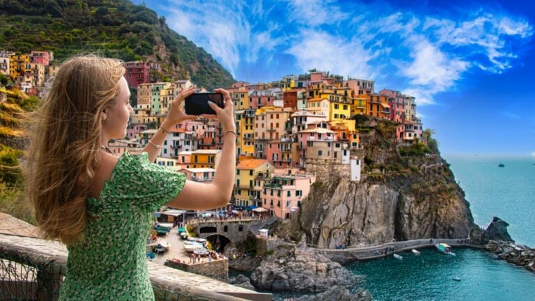 A tourist girl taking a picture of the village of Manarola in Cinque Terre, Liguria, Italy