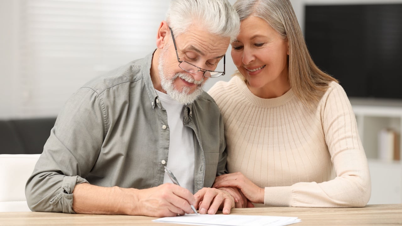 Senior couple signing Last Will and Testament indoors