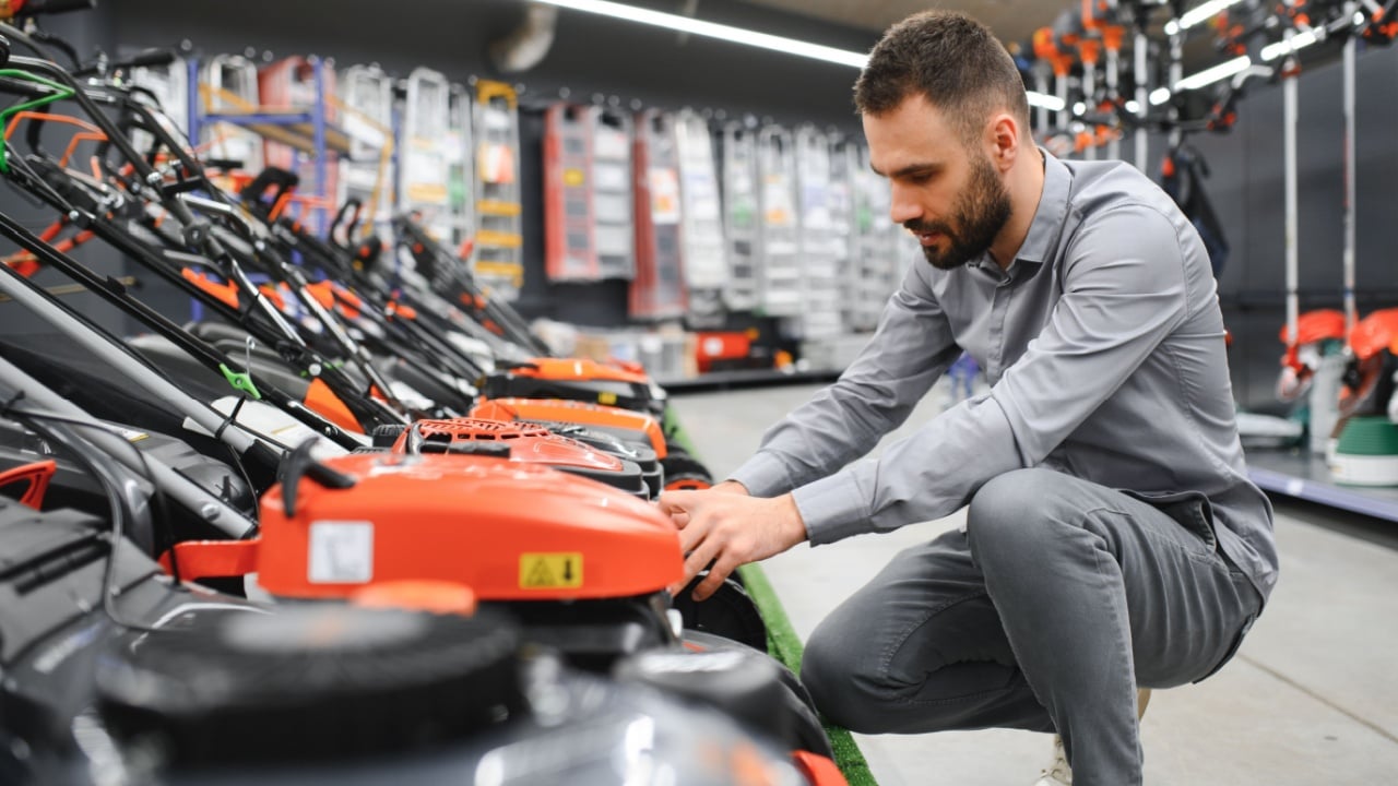 a customer examines new models of lawn mowers in an electrical store for gardeners and horticulturists.