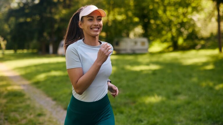 Happy athletic woman running while exercising in nature.