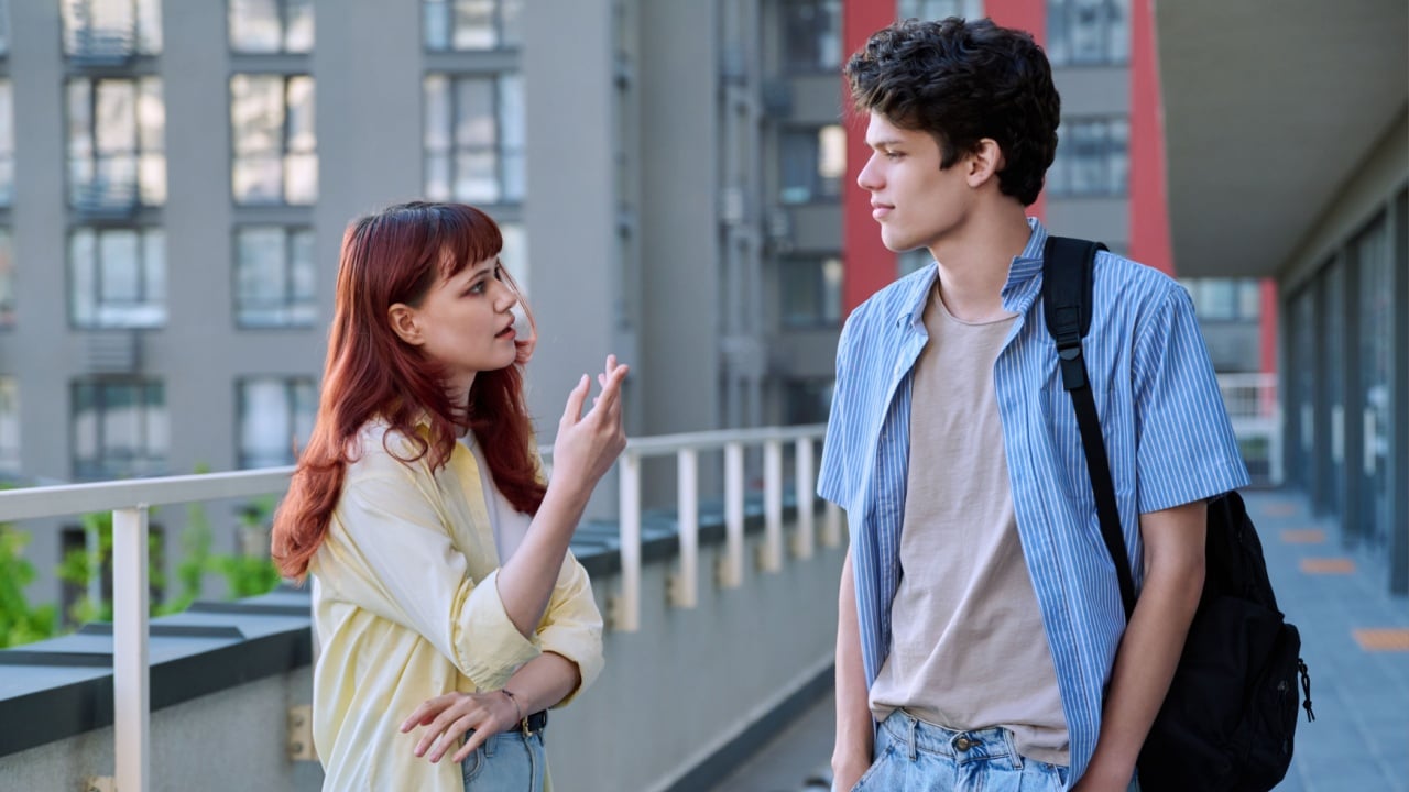 Friends young guy and girl college students talking together, urban outdoor