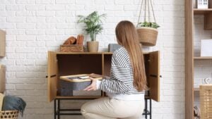 Young woman putting organizers with clothes in cabinet at home