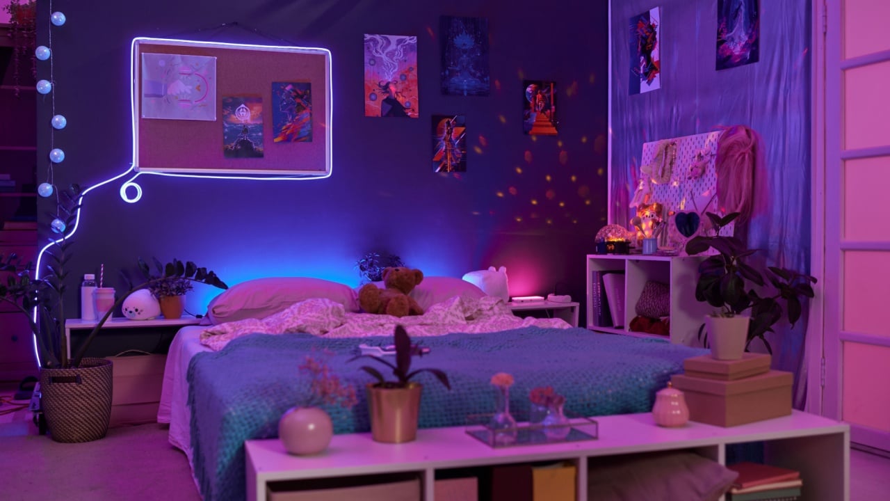Background image of girls room interior with pink and purple neon lights over comfortable bed and fluorescent art copy space