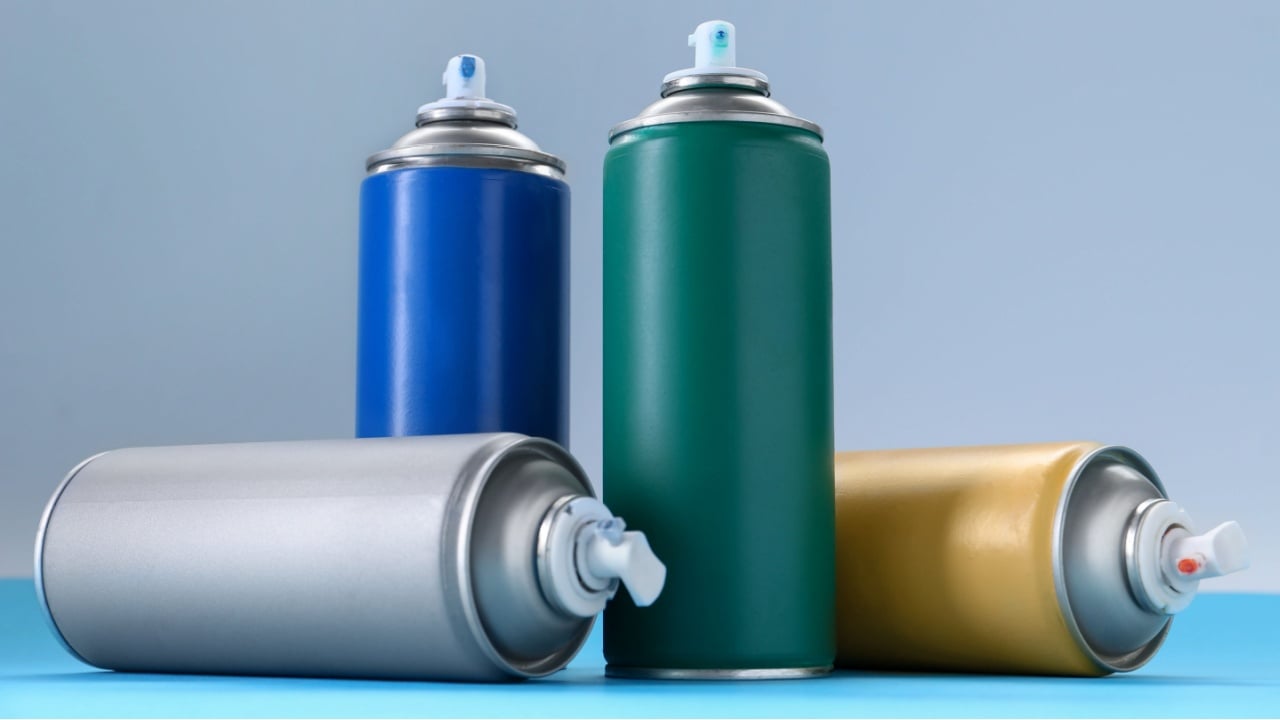 Many spray paint cans on color background
