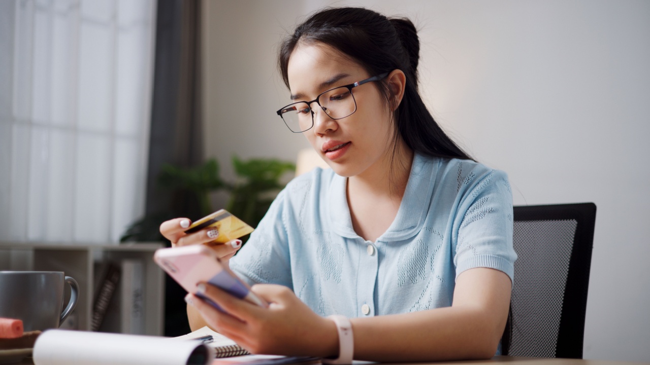 Portrait of Relaxed female freelancer sitting at desk shopping online using a credit card and paying via digital tablet in home office. Work from home