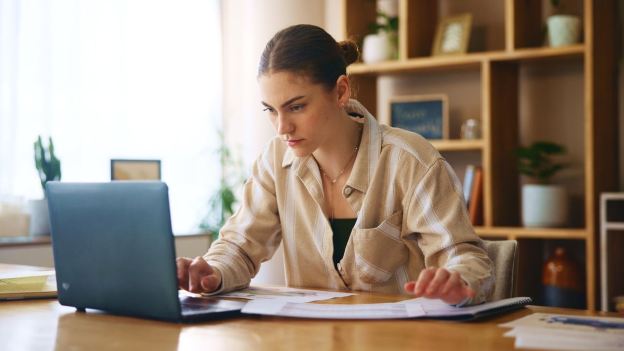 Girl, reading and paperwork with laptop at house for loan approval, bank application and budget planning. Woman online and review documents for accounting, financial payments and investment contract