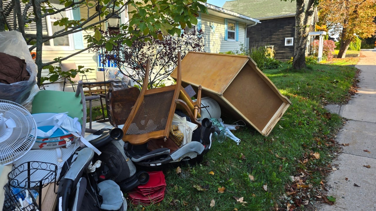 Liverpool, NS, CAN, October 19, 2024 - A pile of trash sitting on a lawn waiting for clean up day to be taken to the dump. An old chair, fan parts, and other junk can be seen.