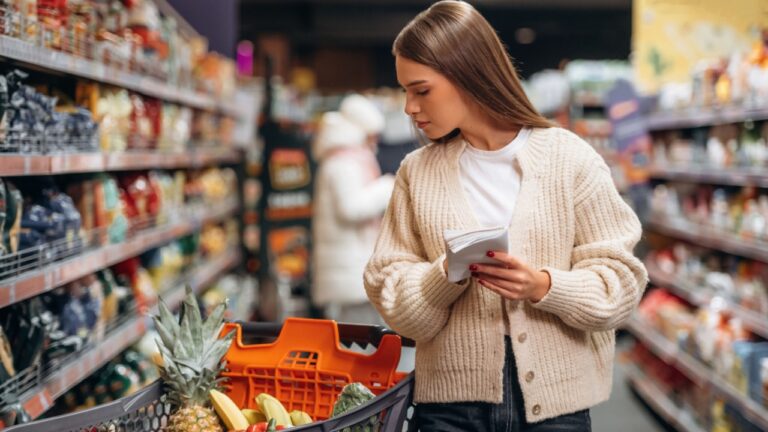Shelves with products. Beautiful woman is in the supermarket.