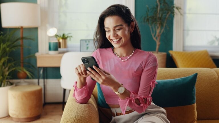 Phone, relax and happy girl scroll in home, reading text and content creator post on social media profile. Mobile, sofa and woman on app for communication, check notification or chat on online forum