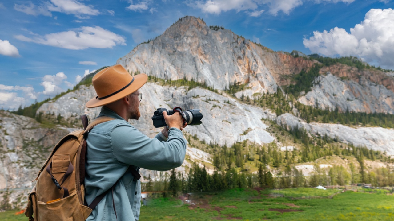 Photographer traveler with hat and backpack capturing stunning Altai mountains in Russia