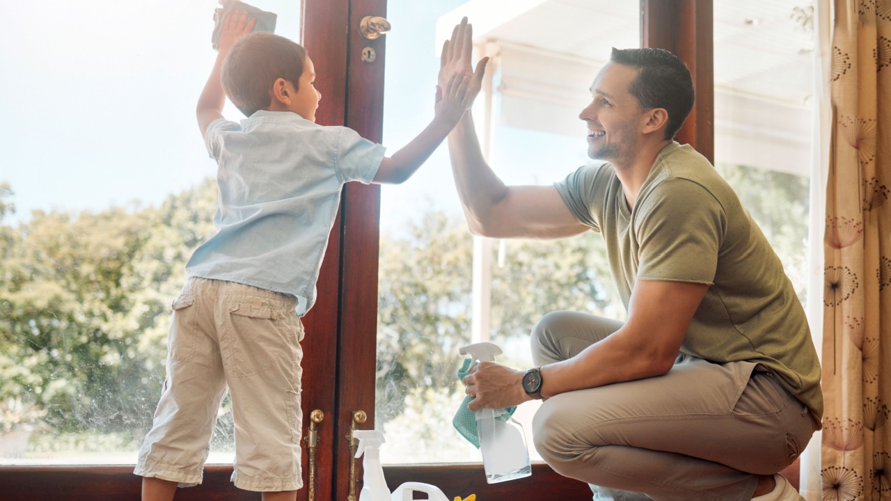 Cleaning, door and high five of father with son in living room of home together for weekend chores. Motivation, success or teamwork of man parent and boy child in apartment with rag and spray bottle