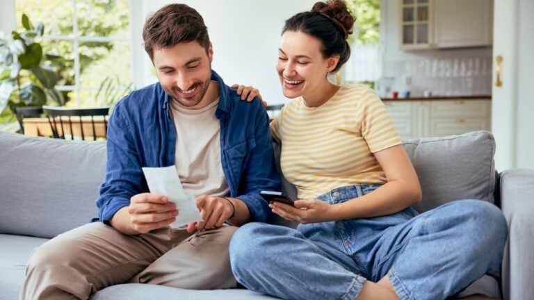 Carefree young couple paying bills managing home finances together