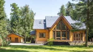 Horizontal photo of wooden house in green forest in sunny weather . Suburban real estate concept.