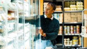 Customer selecting groceries from refrigerated section in supermarket, shopping for fresh, healthy food