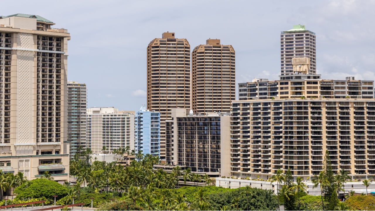 A vibrant urban scene featuring tall buildings amidst tropical palm trees in Honolulu, Hawaii.