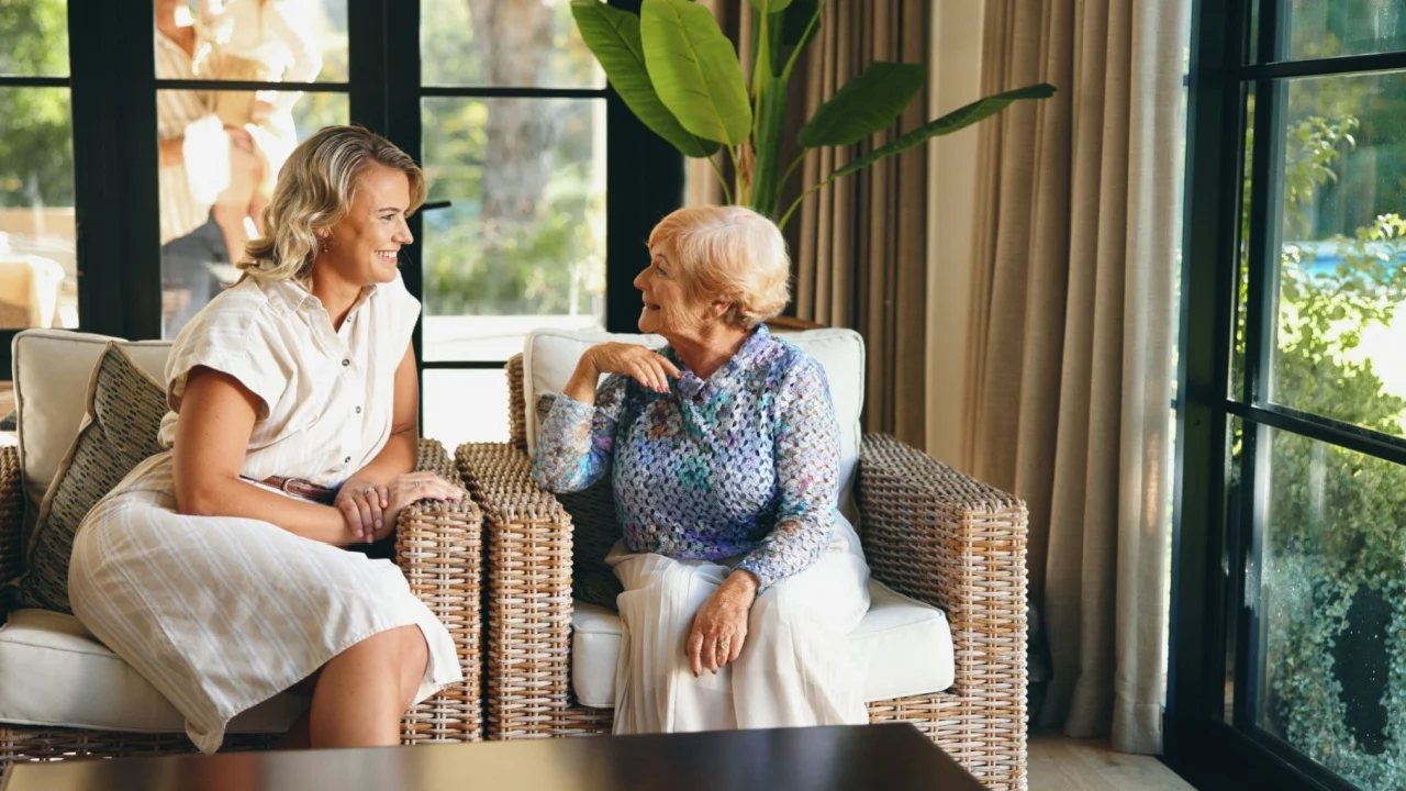 Lounge, senior mother and woman with conversation for bonding together, funny memory and connection. Home, elderly mom and adult daughter with relationship for communication, catch up and support