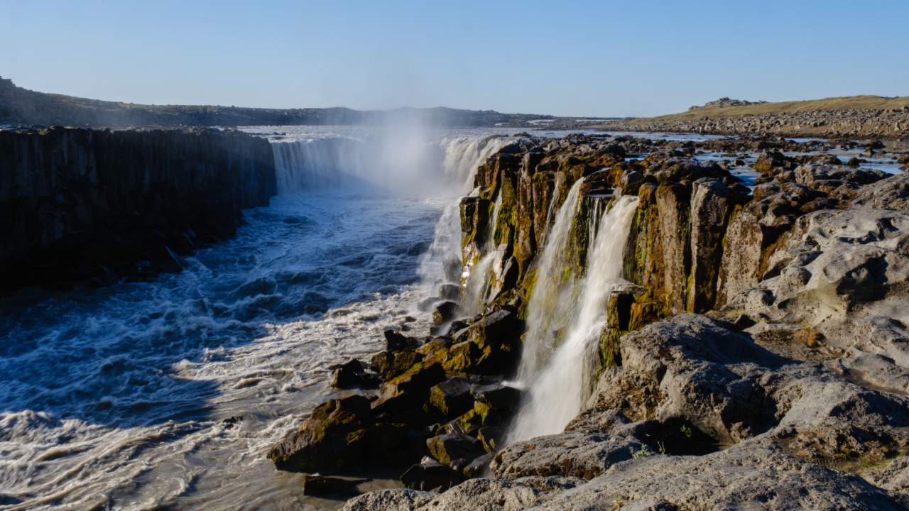 A powerful waterfall flows dramatically over rugged cliffs at Dettifoss, one of Icelands most breathtaking natural wonders. The sound of rushing water echoes in the serene landscape.