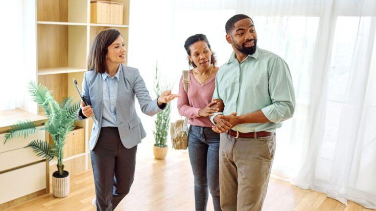 Female Real Estate Agent Selling And Showing The Modern Apartment To His Young Clients That Are Standing Next To Him In The Fancy Apartment