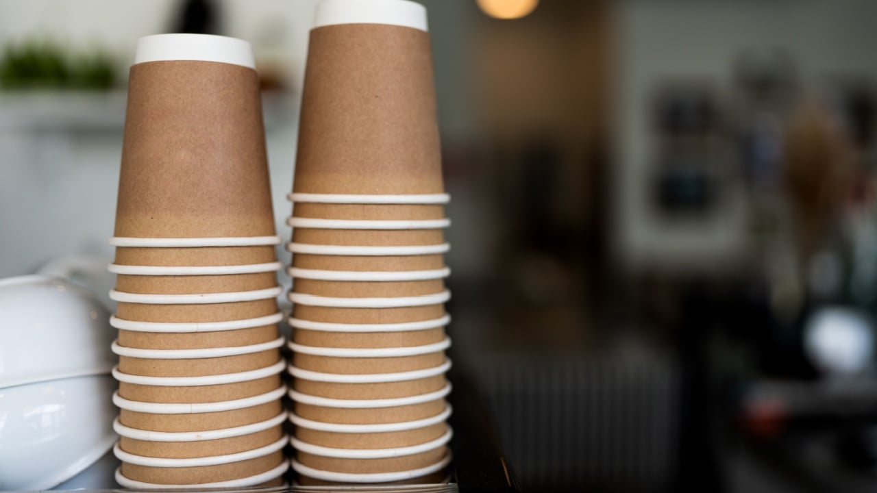 Stacks upside down empty brown takeaway disposable coffee cardboard cups on the coffee machine in the cafe