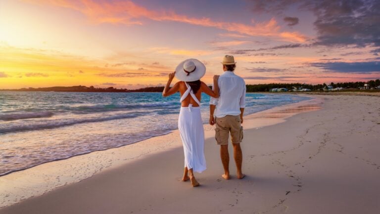 A romantic honeymoon couple stands on a tropical paradise beach and enjoys the beautiful sunrise, Bahamas, Caribbean islands