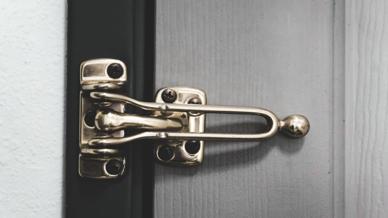 Closeup of a swing bar door lock, also known as a door security guard or flip latch, for an extra layer of security.