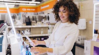 Customer comparing electric toothbrushes in home appliance store, making purchasing decision for oral hygiene