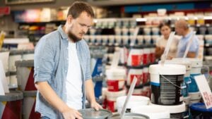 Male shopper carefully selects a can of paint for his home renovation