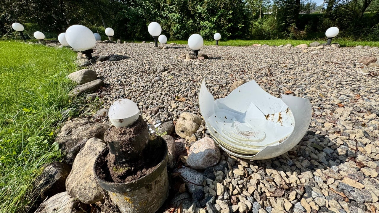 White spherical garden light with broken glass on decorative gravel pathway