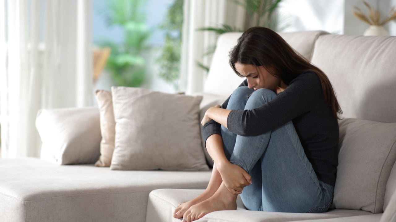 Sad woman complaining alone sitting on a sofa at home