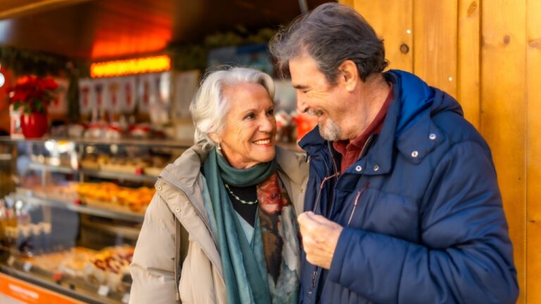 Happy senior couple smiling and enjoying time together during christmas holidays at a winter market