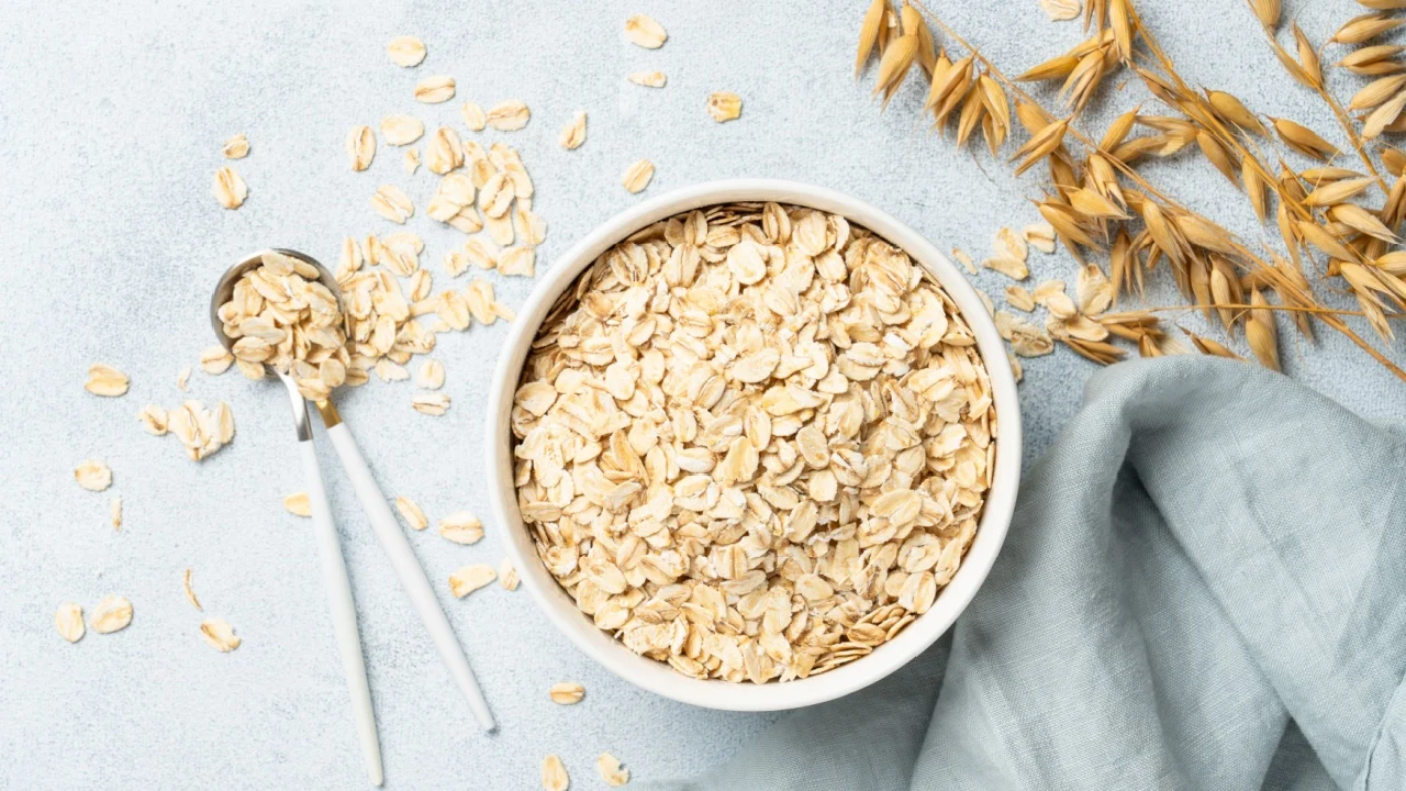 Rolled oats flakes in a wooden bowl with ears.