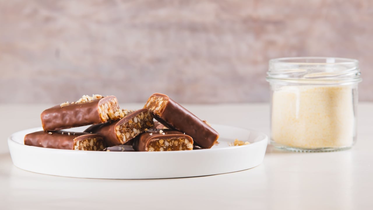 Protein bars with nuts on plate and protein powder in jar on table