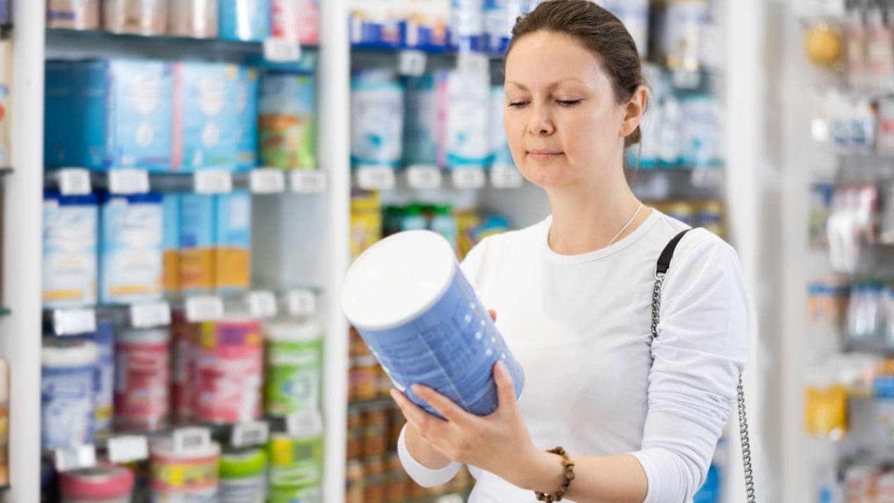Adult woman buyer in casual clothes chooses baby formula in pharmacy