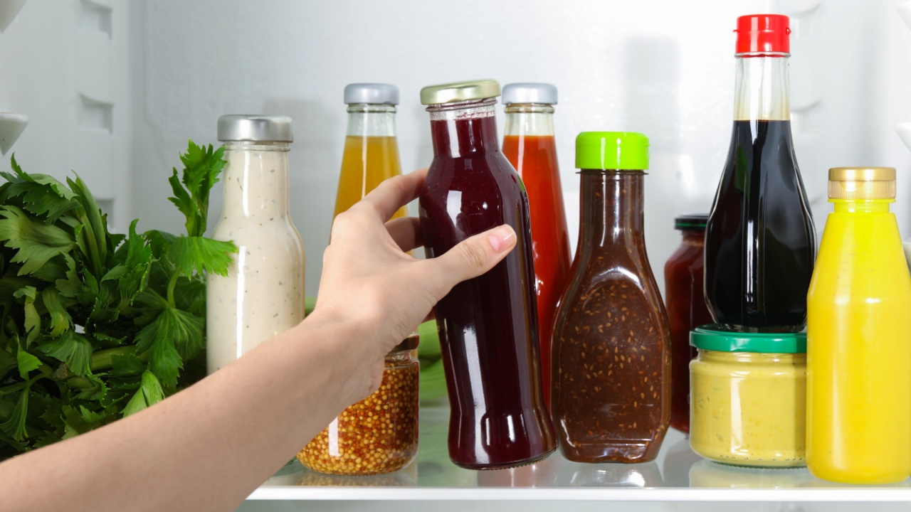 Woman taking bottle of tasty cranberry sauce from fridge,