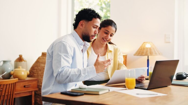 Home, finance and happy couple with laptop, discussion and online reading with savings. Smile, insurance and man with woman, paperwork and pc with mortgage, check expenses and investment plan