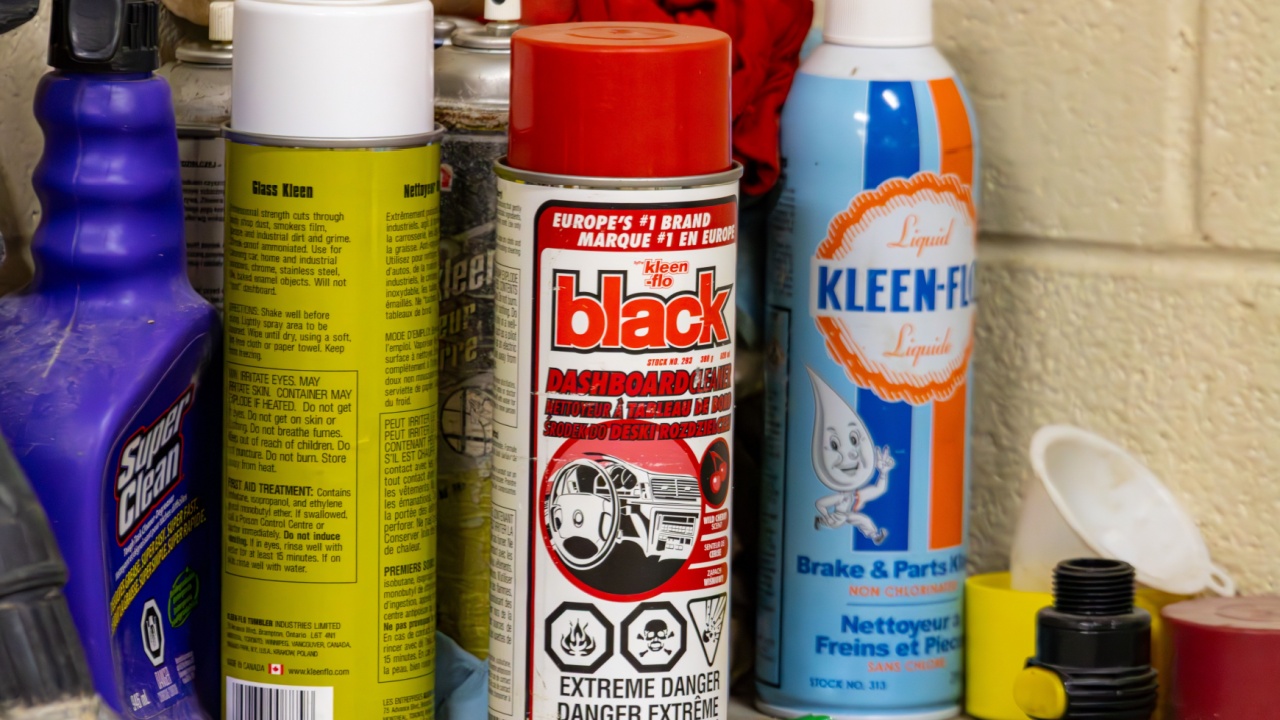 Canada, Quebec, 03 December 2025 : Colorful automotive cleaning products stand on cluttered garage workshop shelf