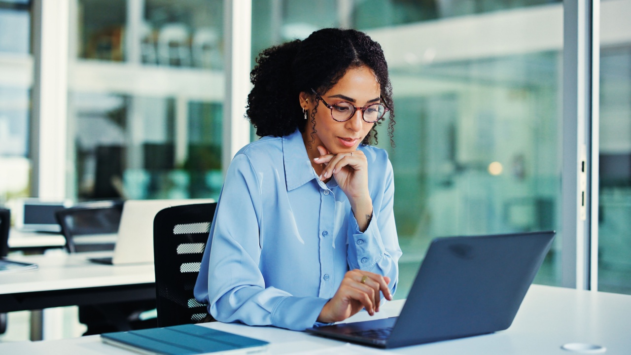 Reading, employee and woman with laptop, office and risk assessment for investment proposal or info. Business, financial analyst and person with tech for asset management, online and budget review