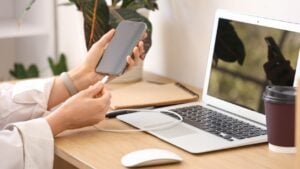 Female hands charging mobile phone at desk in office, closeup